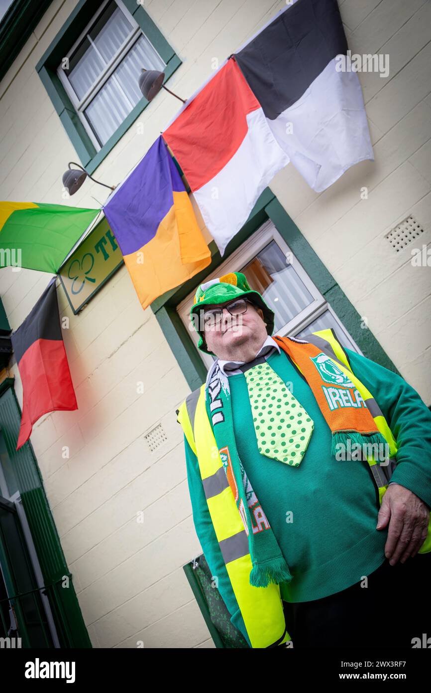 Man with green Irish clothing stands outside Warrington Irish Club on St Patrick's Day 2024 Stock Photo