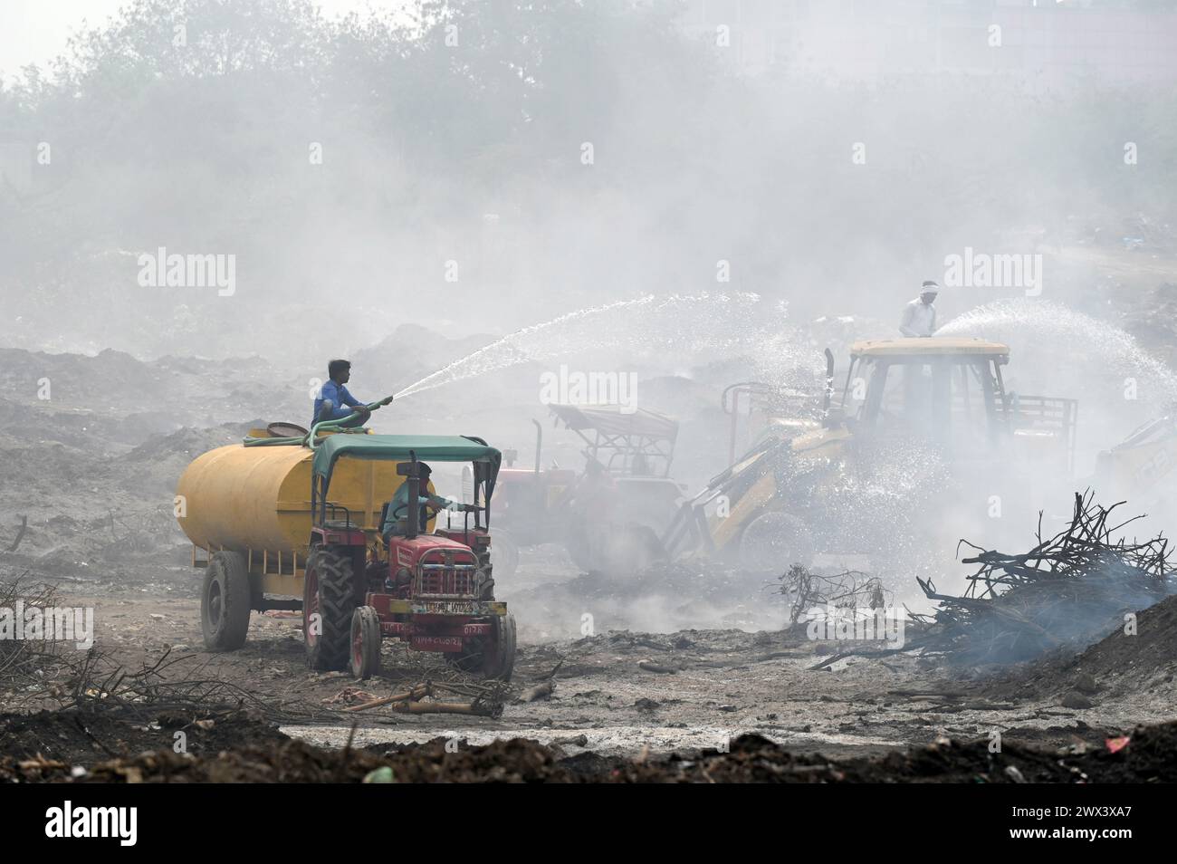 Noida, India. 27th Mar, 2024. NOIDA, INDIA - MARCH 27: Firefighters try to douse a fire at horticulture waste dumping yard in Sector 32 on March 27, 2024 in Noida, India. The fire started around 6pm on Monday and has engulfed an area roughly 1.5km wide and 2km long in Sector 32, GB Nagar fire chief said. All horticulture waste from across Noida is dumped at that plot for conversion into compost. (Photo by Sunil Ghosh/Hindustan Times/Sipa USA) Credit: Sipa USA/Alamy Live News Stock Photo
