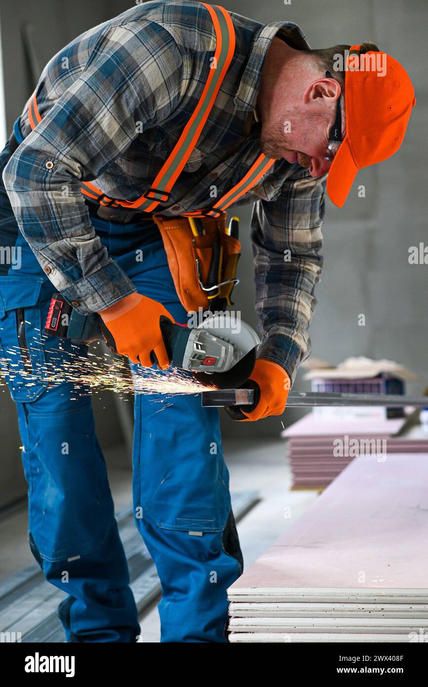 a worker saws a plasterboard profile using an angle grinder. Stock Photo