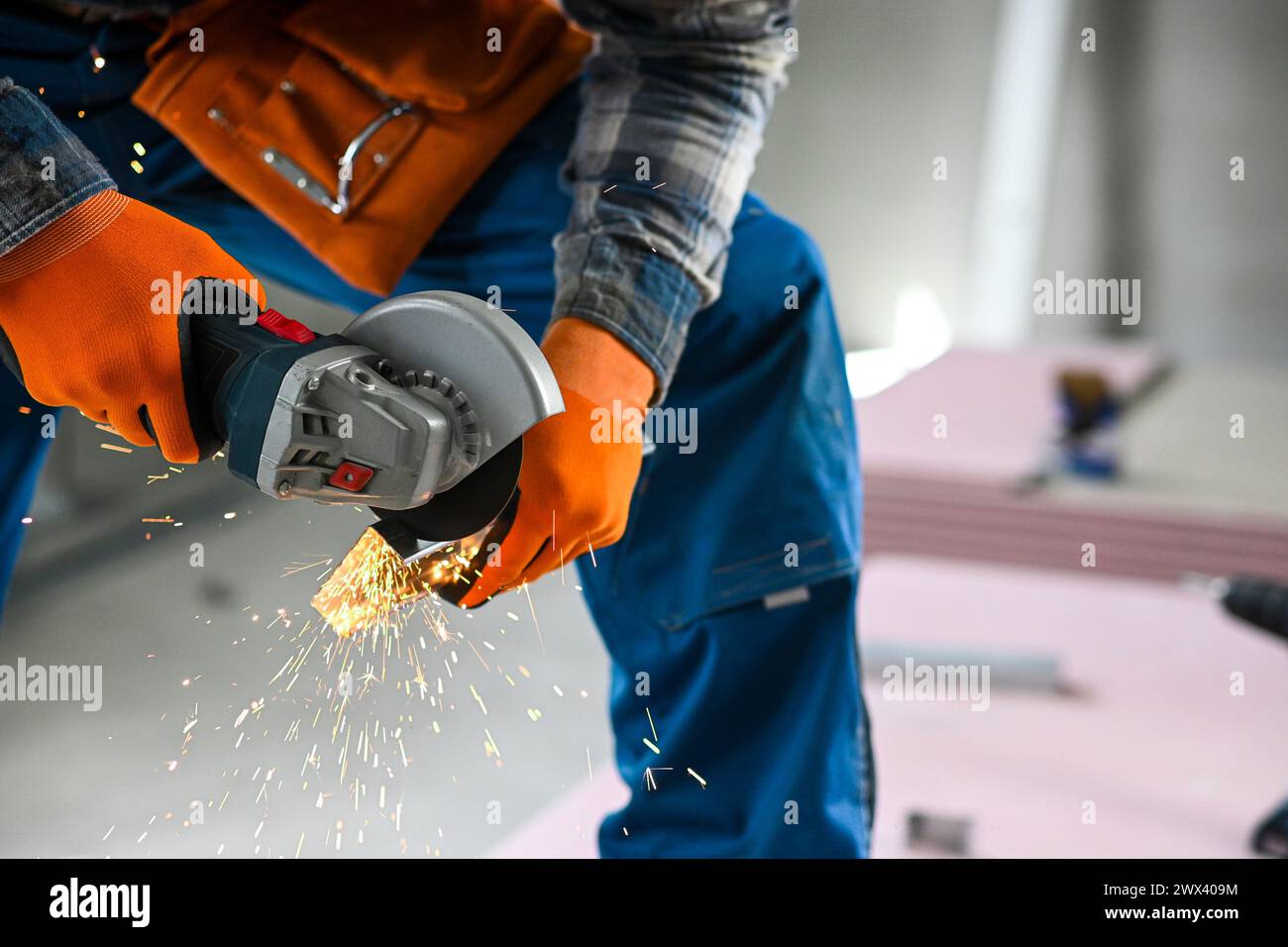 a worker saws a plasterboard profile using an angle grinder. Stock Photo
