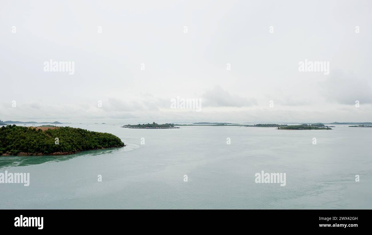 Groups of small islands stretched into the far horizon, with calm sea and gloomy sky. View from on top of Barelang Bridge, Indonesia. Stock Photo