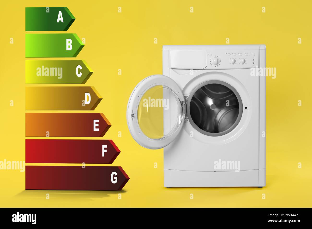 Energy efficiency rating label and washing machine on yellow background Stock Photo