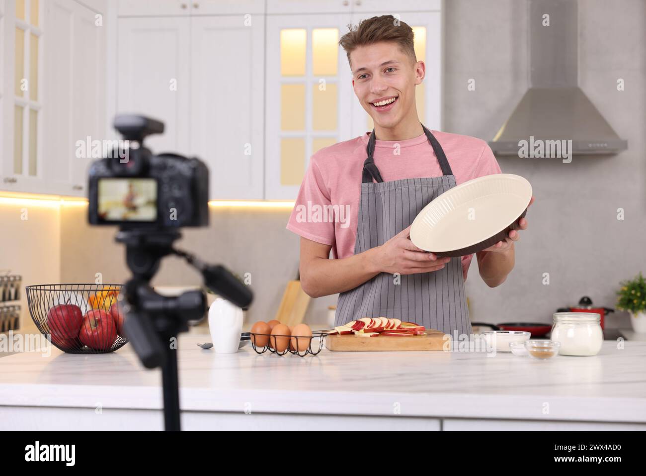 Smiling food blogger explaining something while recording video in kitchen Stock Photo