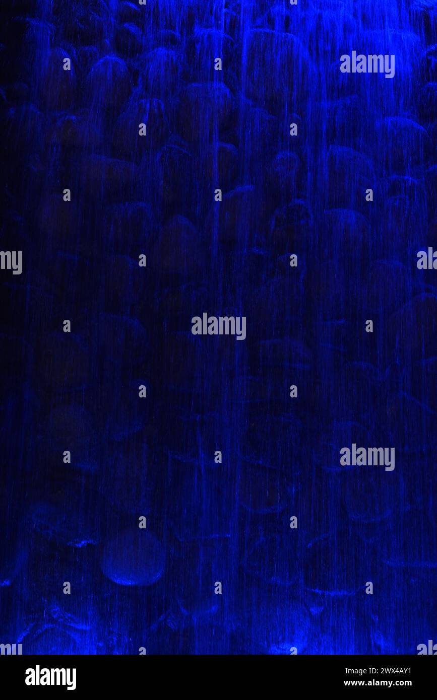 Vertical image of an artificial waterfall lit by blue lights Stock Photo