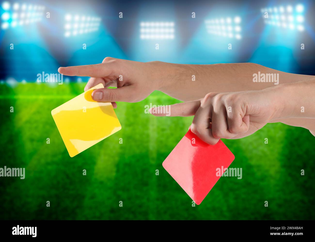 Referee holding red and yellow cards at stadium, closeup Stock Photo