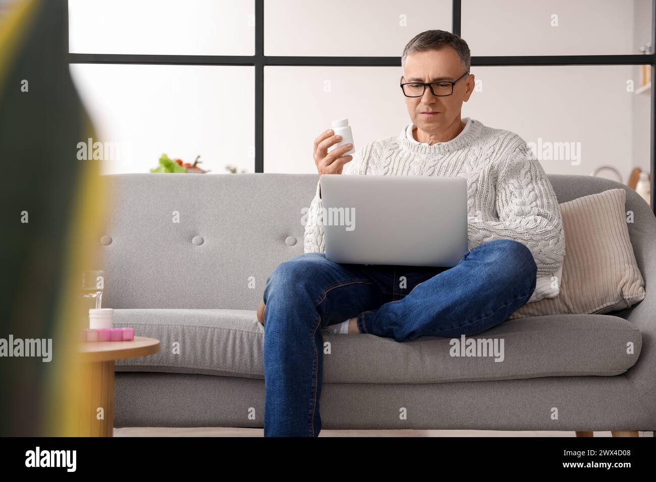 Middle-aged man checking pills description online at home Stock Photo