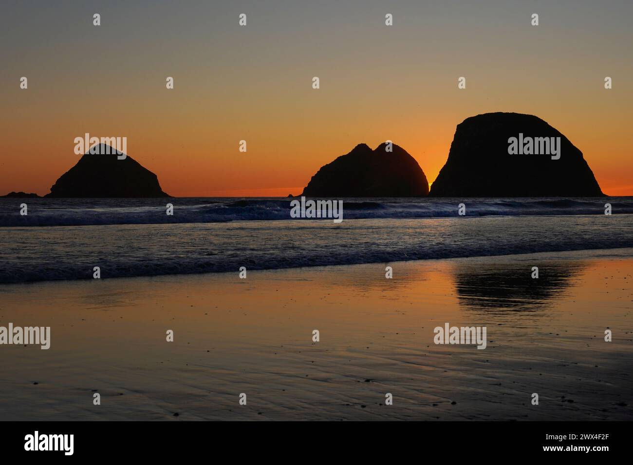 Sunsetting behind three sea stacks on the Oregon coast Stock Photo