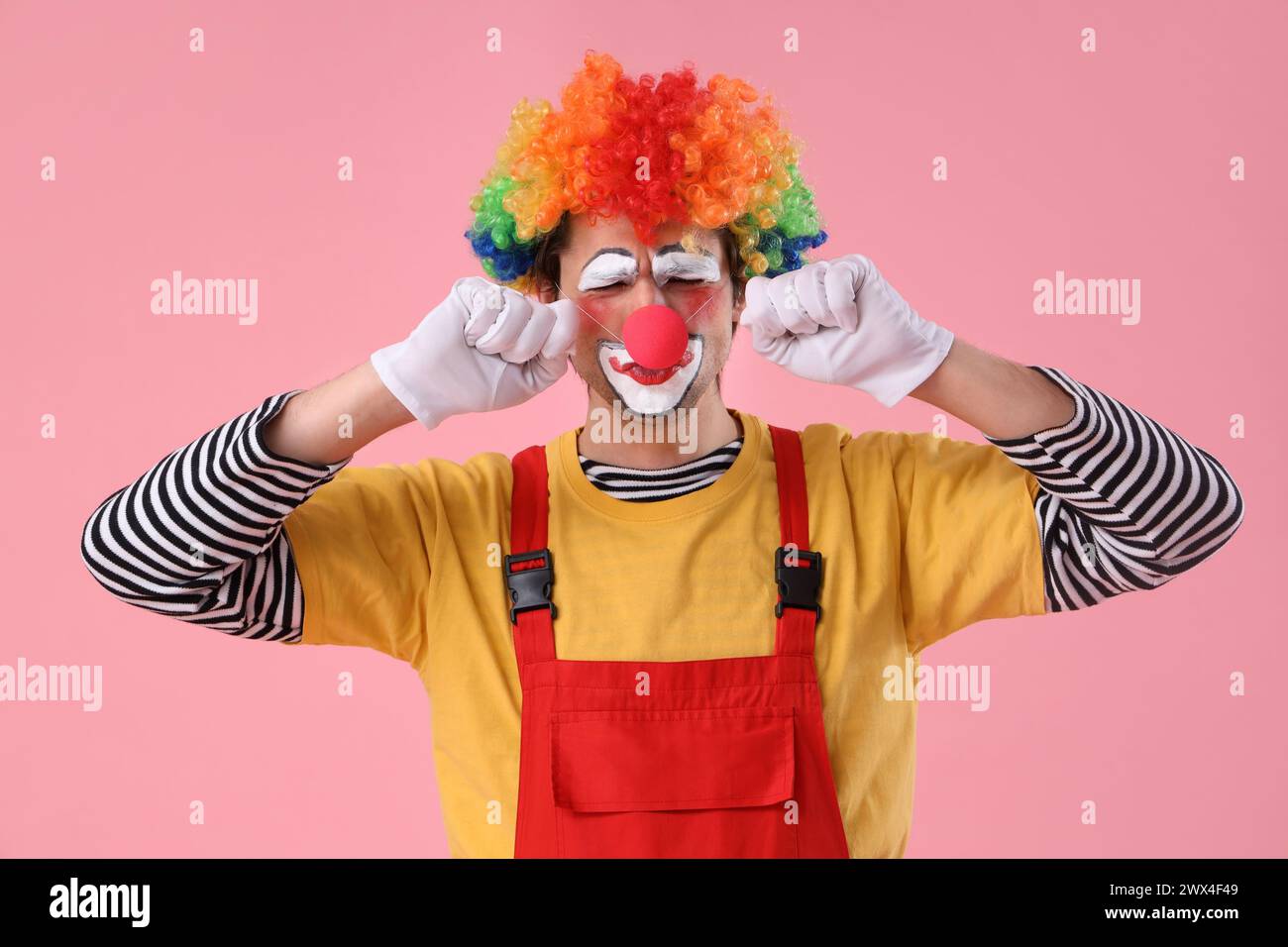 Portrait of sad clown on pink background. April Fool's day celebration Stock Photo
