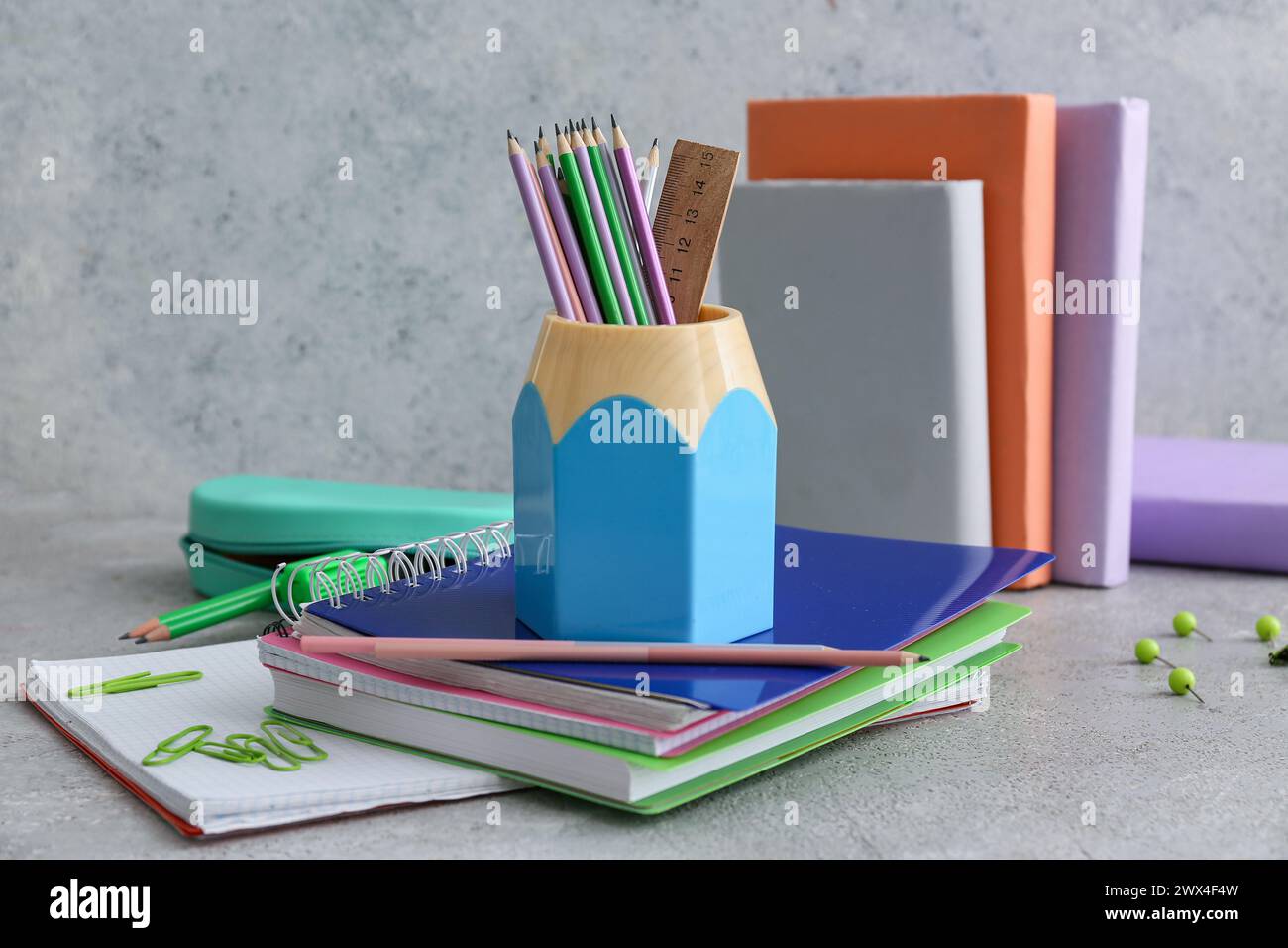 Pencil holder and notebooks on table against grey background Stock Photo