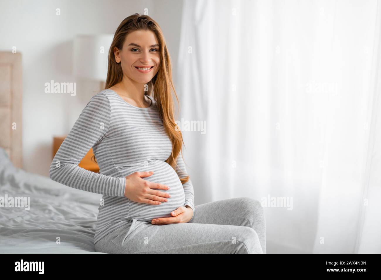 Expectant mom smiling on bed Stock Photo - Alamy