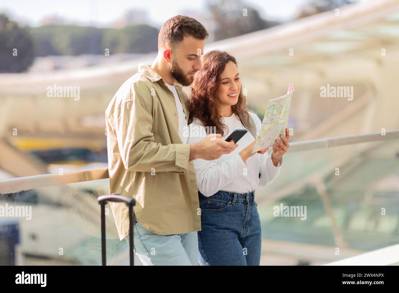 Couple reading map and using phone together Stock Photo