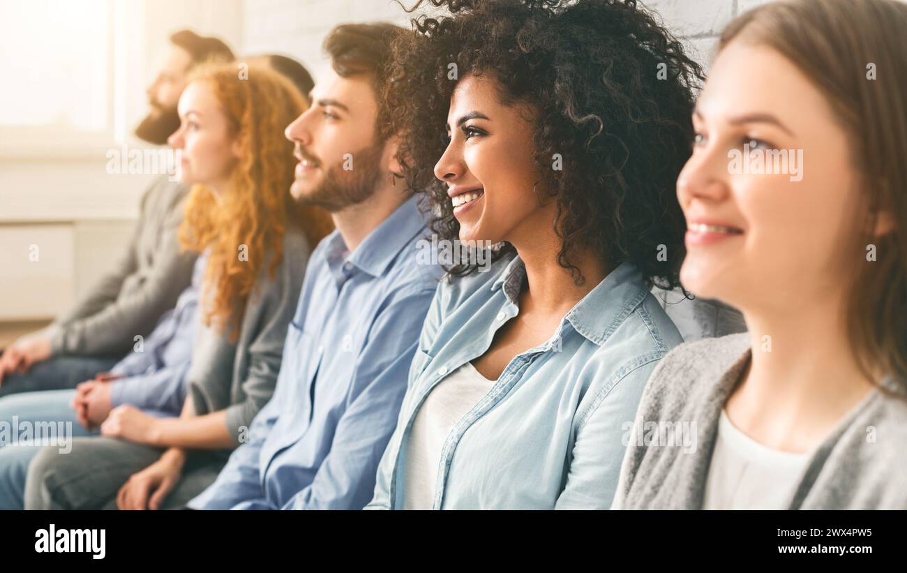 Diverse millennial group sitting in row, waiting for something Stock Photo