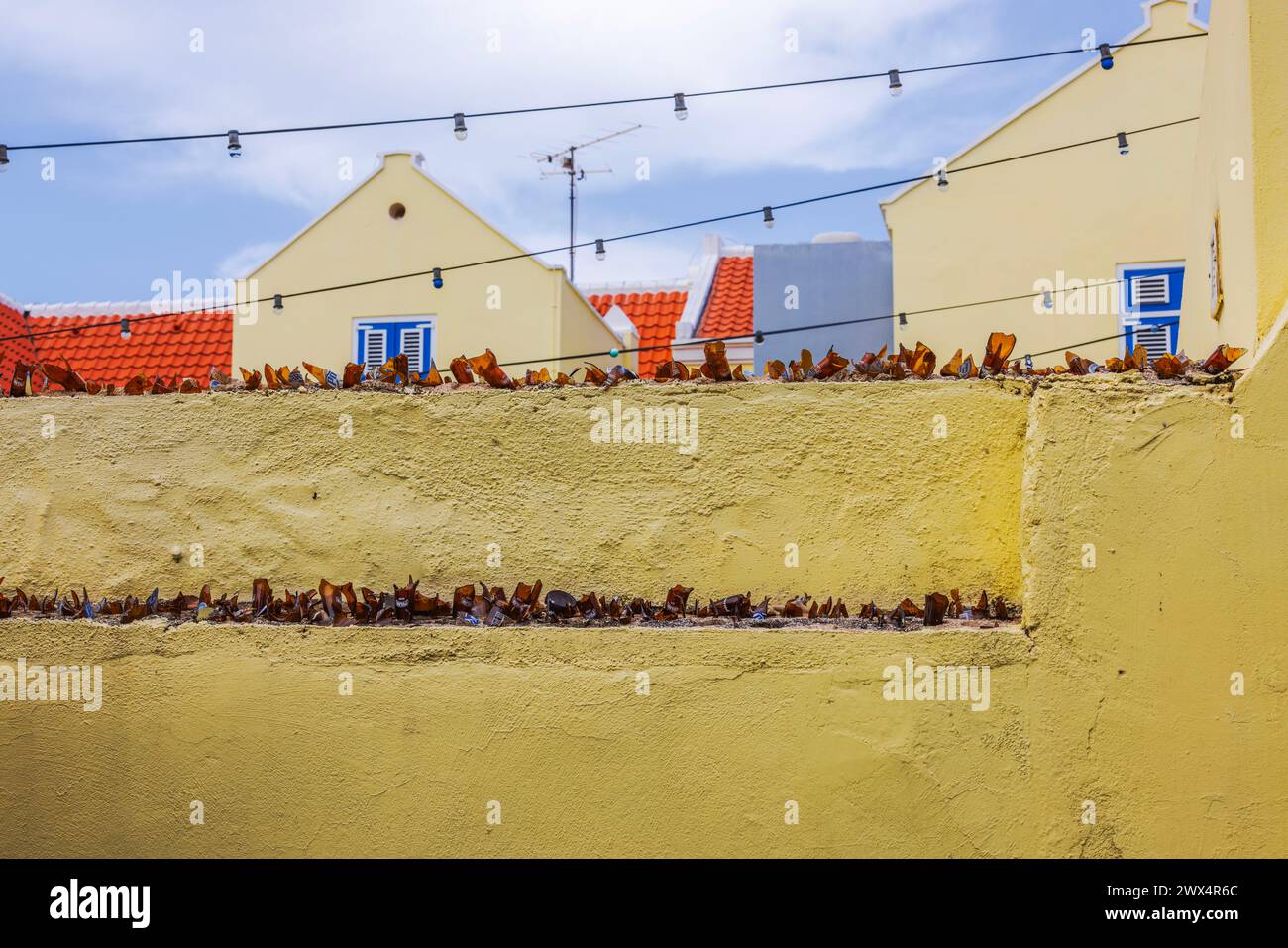 Close-up view of a defense wall topped with broken bottle shards as a protective measure. Willemstad. Curacao Stock Photo
