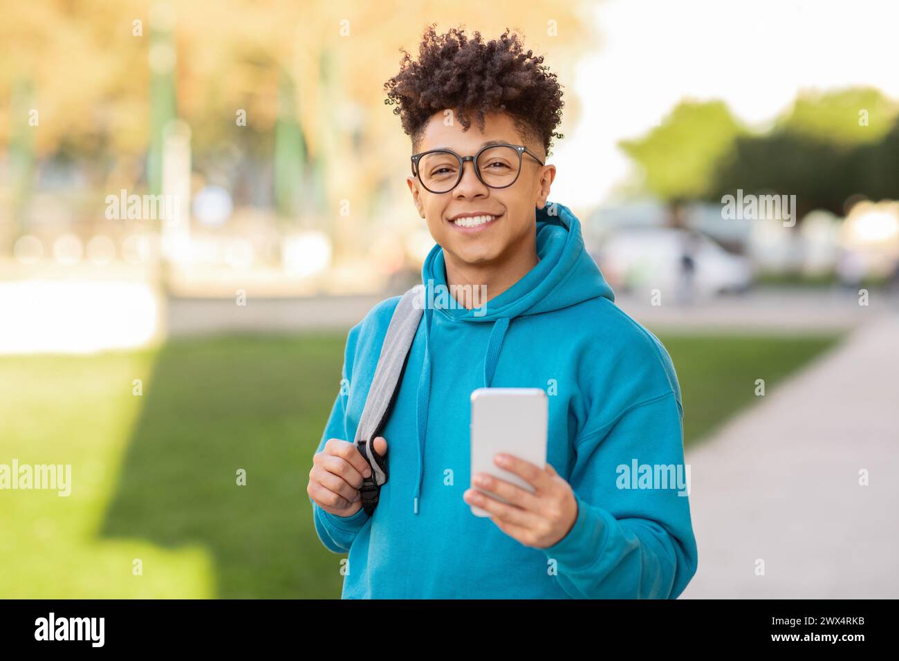 Smiling student using phone in city Stock Photo