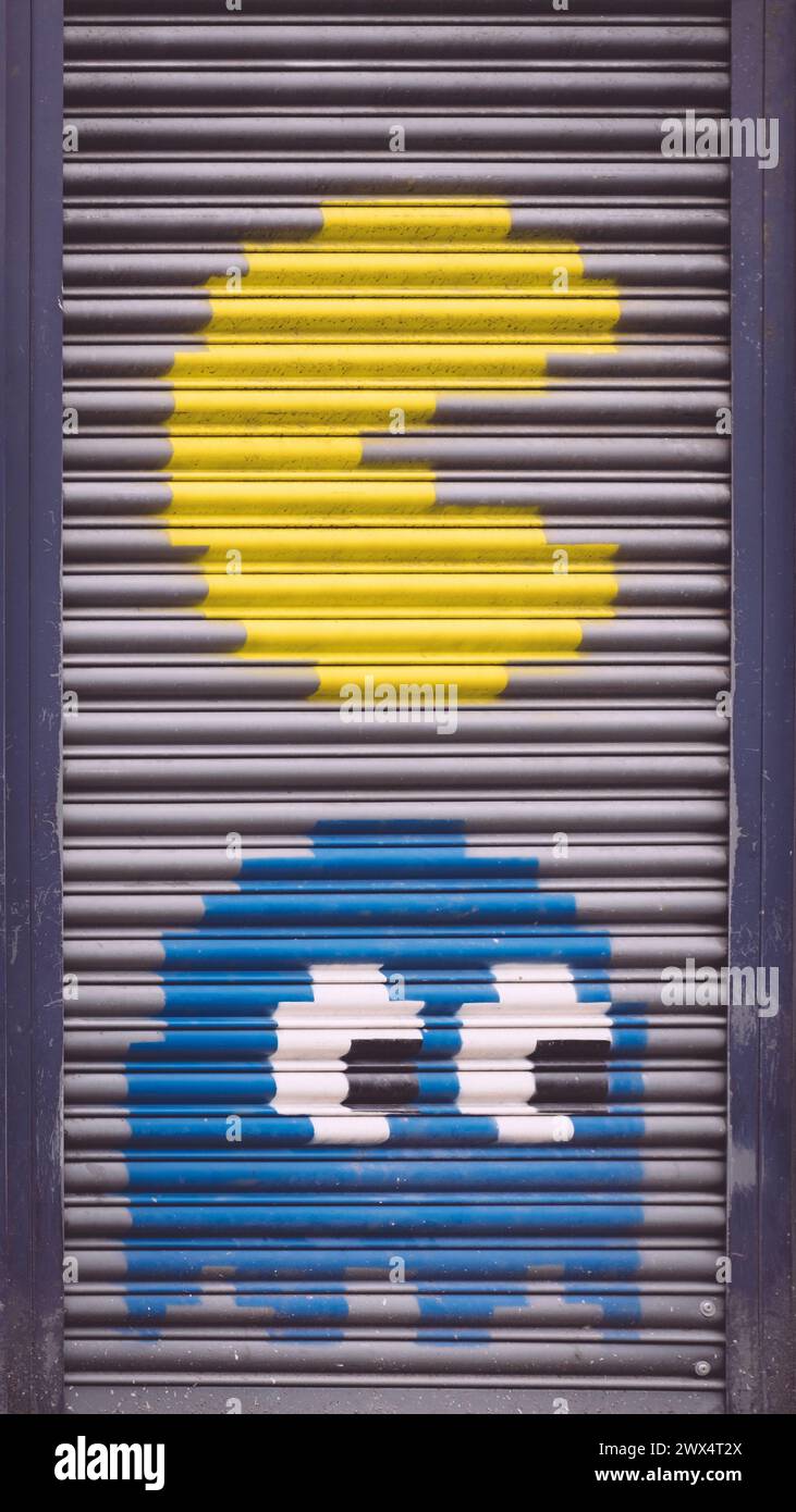 Pac man and a ghost mural on a roller shutter door in Manchester.  Classic retro arcade game Stock Photo