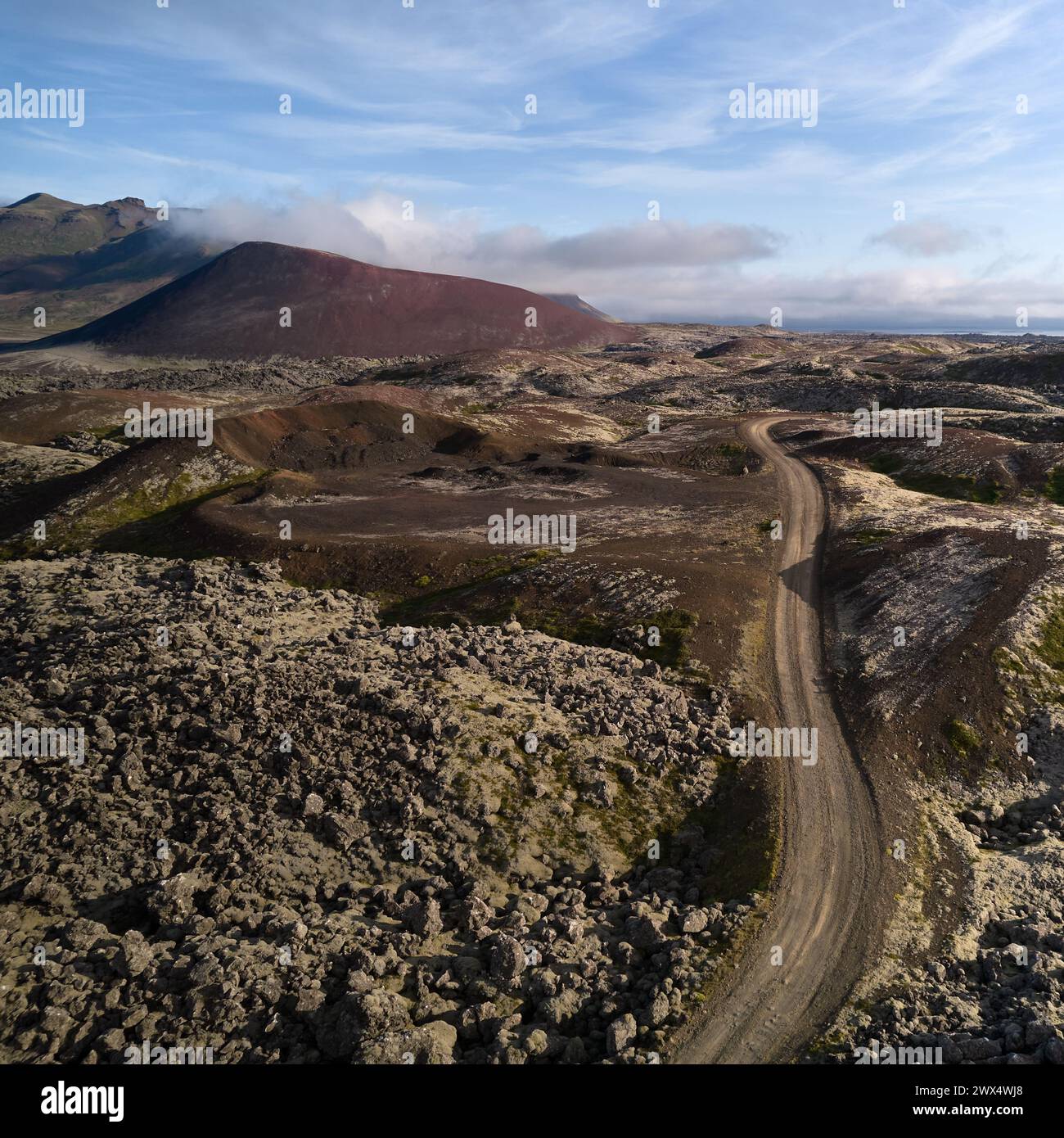 A view of the dirt road stretching to the horizon among the lava fields. Top view, photo taken from the drone. Helgafellssveit, Iceland. Stock Photo