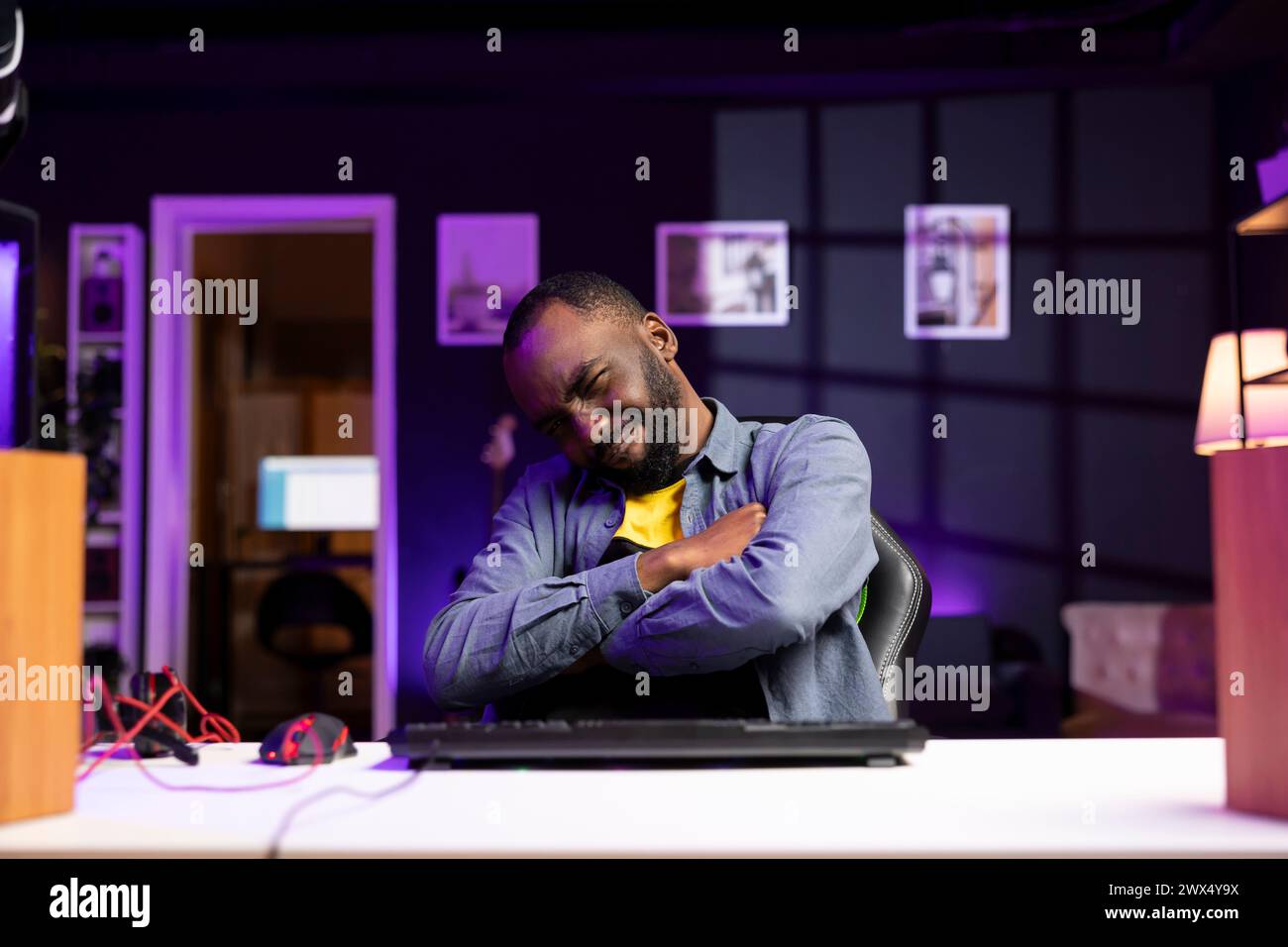 Gamer wincing while looking at computer monitor after losing singleplayer videogame, seeing game over screen. Man flinching seeing his character getting destroyed in difficult game level Stock Photo