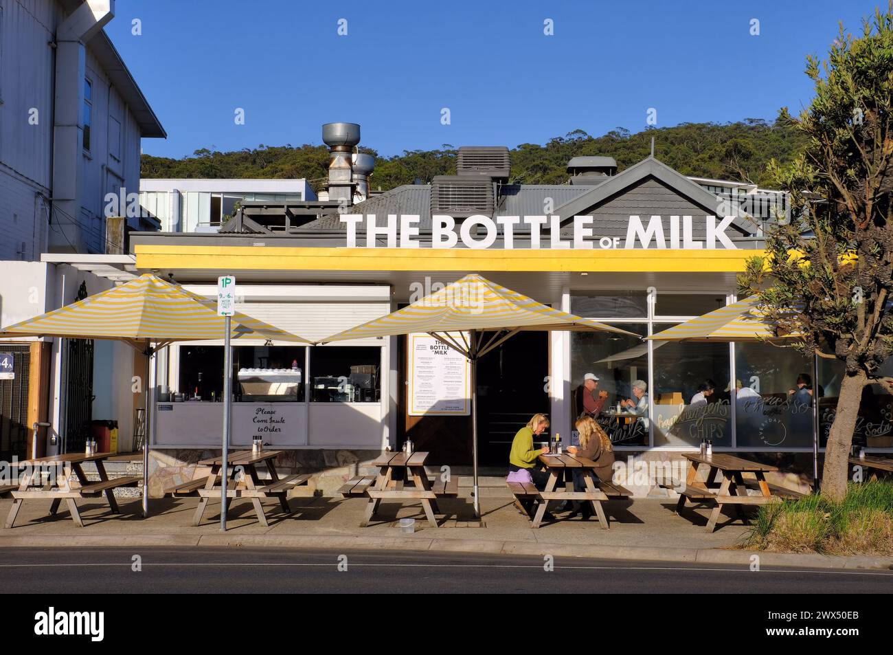 Lorne: The Bottle of Milk café with outdoor seating, umbrellas and diners at Lorne Stock Photo