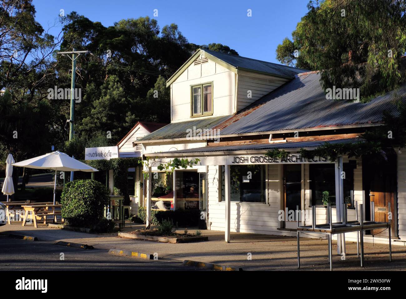 Lorne: Riverbank Café with outdoor seating and umbrellas and architect firm soon after sunrise at Lorne Stock Photo