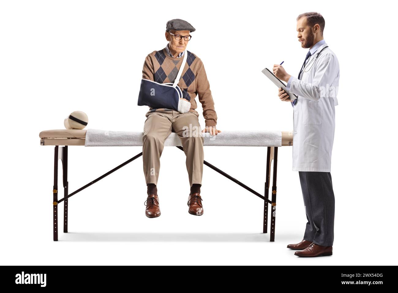 Injured elderly man with a broken arm sitting on a medical bed with a doctor isolated on white background Stock Photo