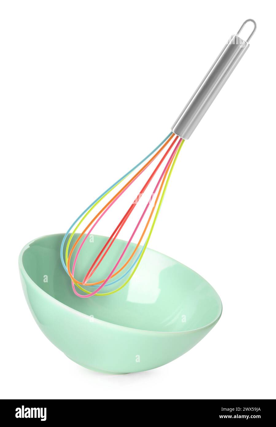 Colorful whisk and light green bowl in air on white background. Cooking ...