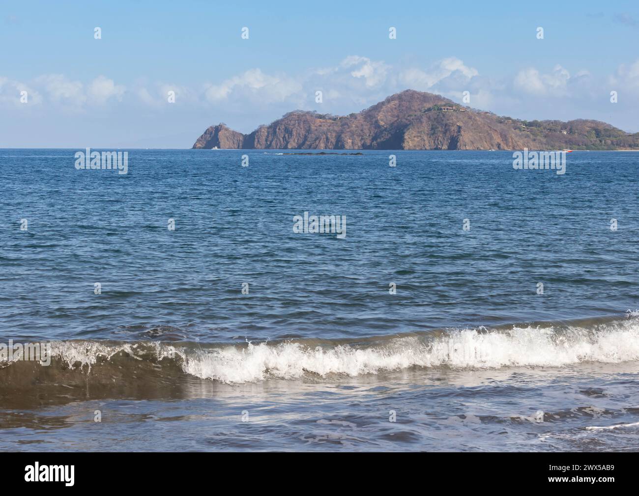 Wave near the beach and island in the distance in Playa Hermosa Costa Rica Stock Photo