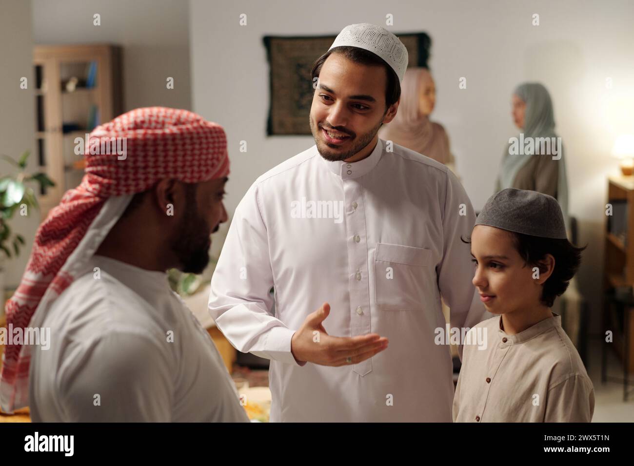 Selective focus shot of happy Muslim man introducing his son to distant relative at family gathering on Uraza Bayram day Stock Photo