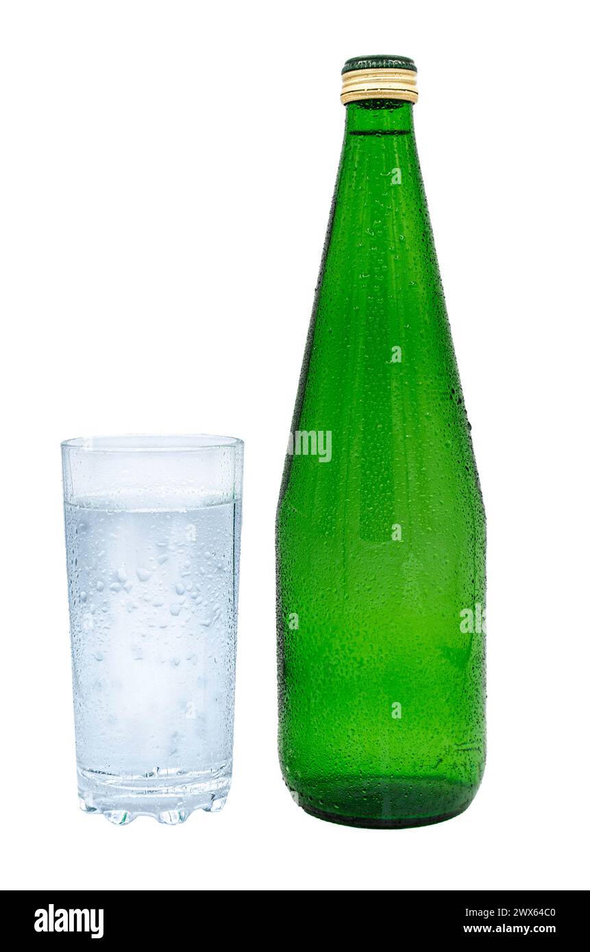 Close-up. Green bottle of mineral water and a glass with water drops ...