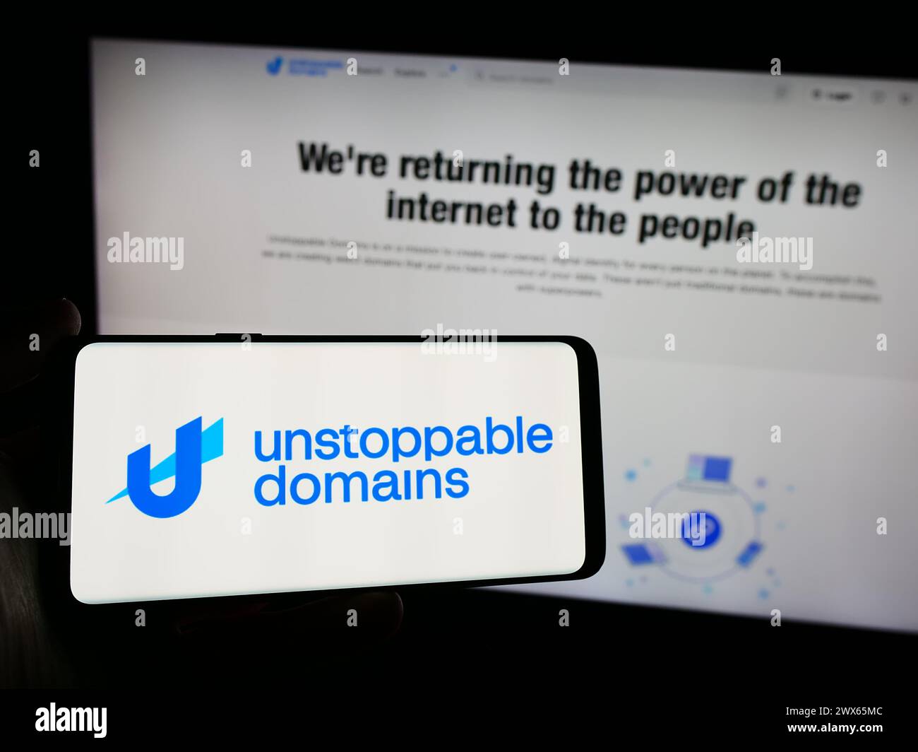 Person holding smartphone with logo of US blockchain company Unstoppable Domains Inc. in front of website. Focus on phone display. Stock Photo