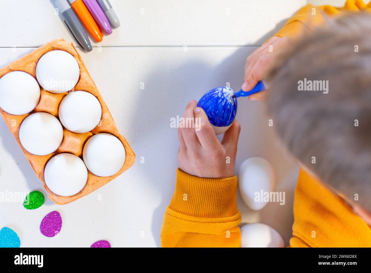 Child painting an easter egg seen from above Stock Photo