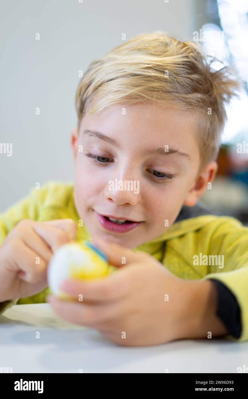 Happy child decorating an Easter egg with marker Stock Photo
