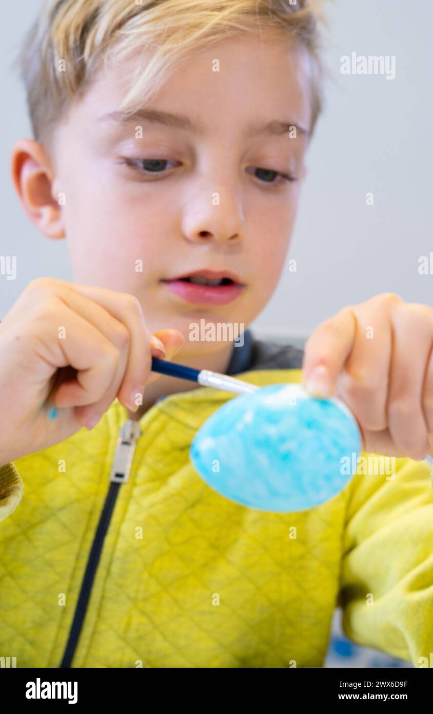 Concentrated Child Decorating An Easter Egg Stock Photo - Alamy