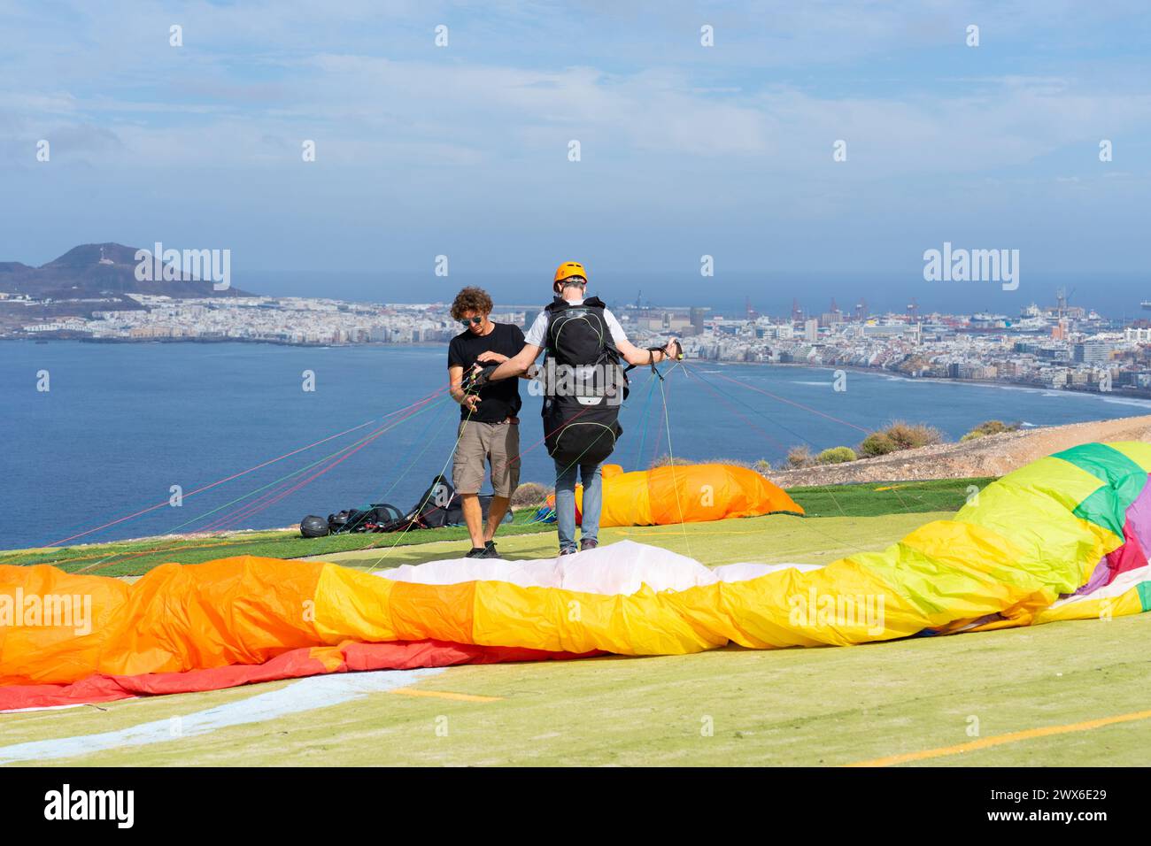 Man learning to paraglide on an island and paragliding teacher checking that all the material is correct Stock Photo