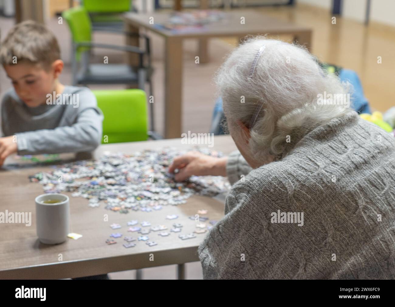 Senior woman doing a puzzle with a child in a nursing home Stock Photo