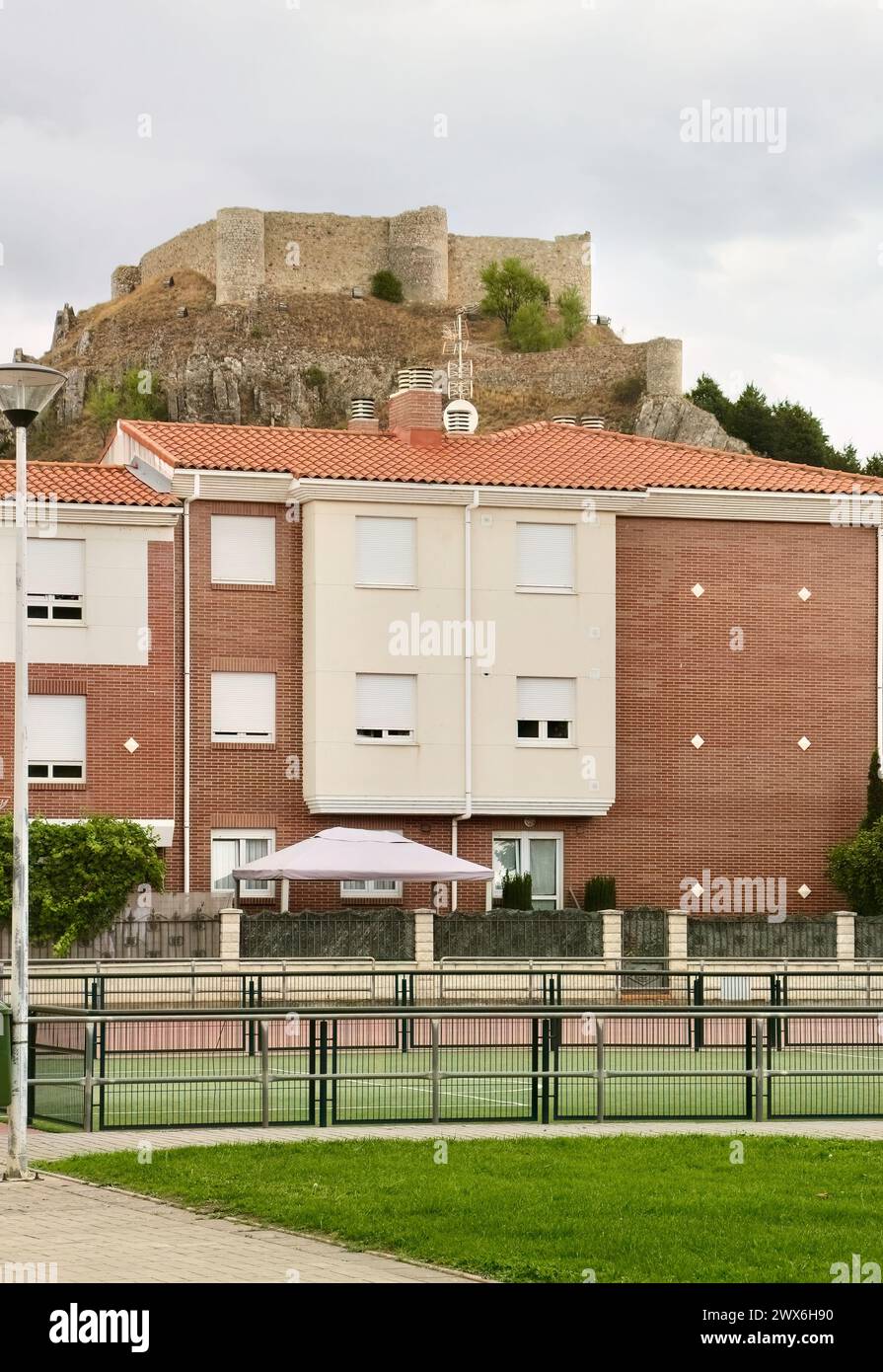 Ruined eleventh century hilltop castle overlooking a modern apartment building in the town of Aguilar de Campoo Palencia Castile and Leon Spain Stock Photo