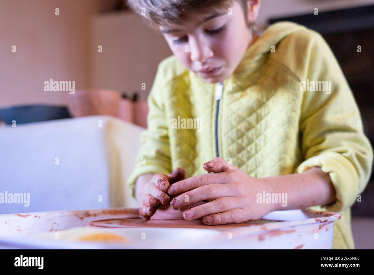 Concentrated boy learning to make ceramic pieces on the potter's wheel Stock Photo