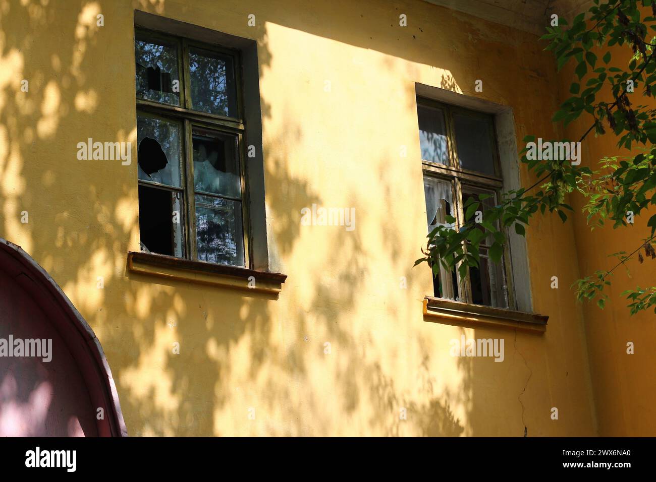 Broken glass in the windows, yellow facade of an abandoned building ...