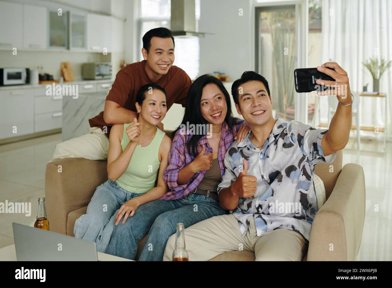 Happy Vietnamese man taking selfie with friends at home Stock Photo