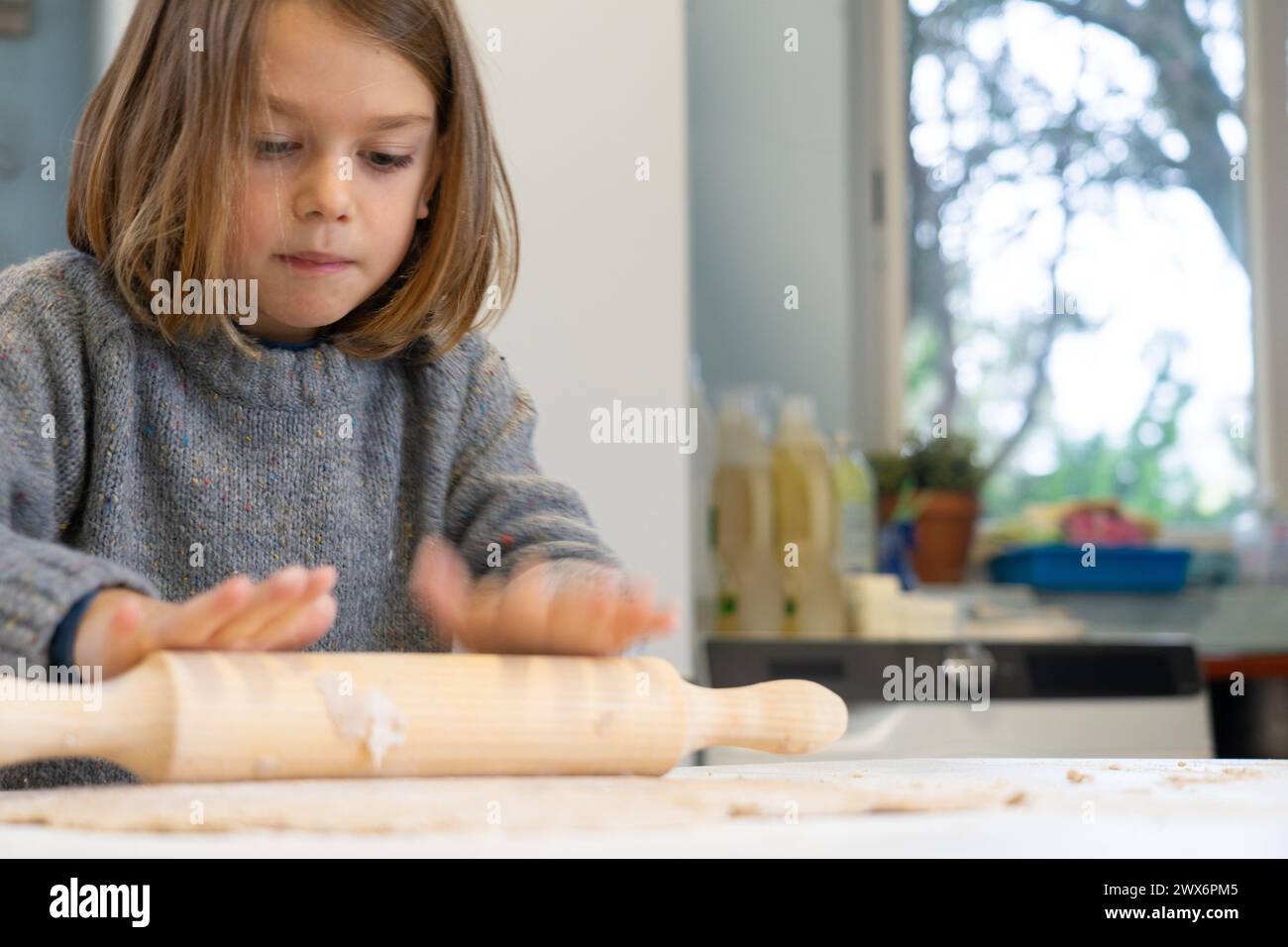 Boy stretching a pizza dough with a rolling pin Stock Photo
