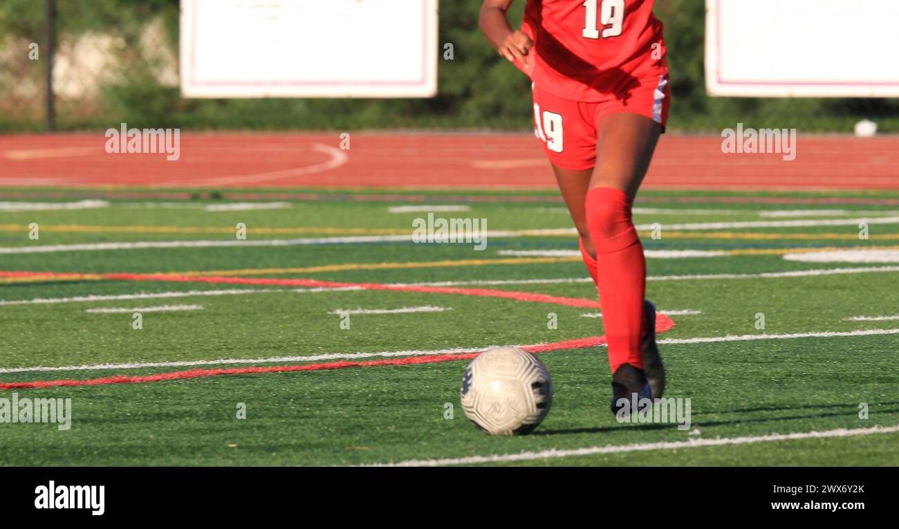 One high school girls soccer player kicking the soccer ball on a free kick during a soccer game. Stock Photo