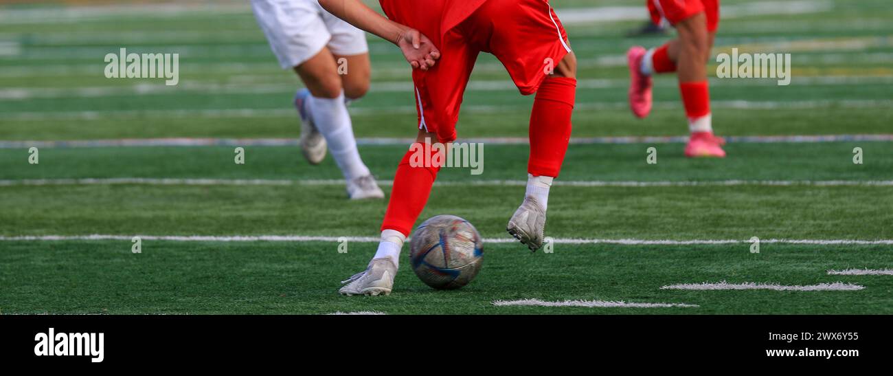 Rear view of a soccer player dribbling the ball upfield during a game. Stock Photo