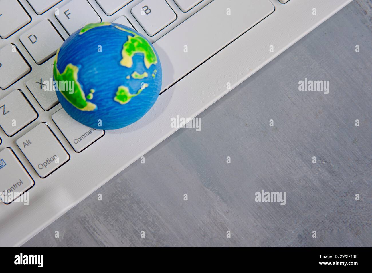 A globe on a white computer keyboard with copy space. Global communication, computer network, globalization concept. Stock Photo