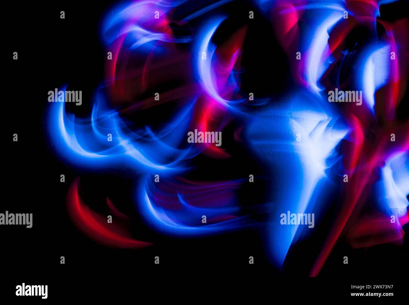Abstract irregular blue and red lights on black background. Long exposure. Light painting photography. Stock Photo