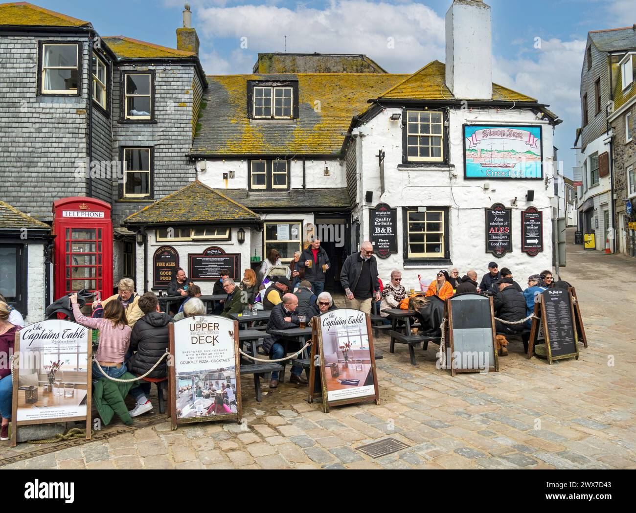 Al Fresco customers, diners and drinkers outside the 'Sloop Inn' one of the oldest Inns in Cornwall (Circa 1312), St. Ives, Cornwall, England, UK Stock Photo