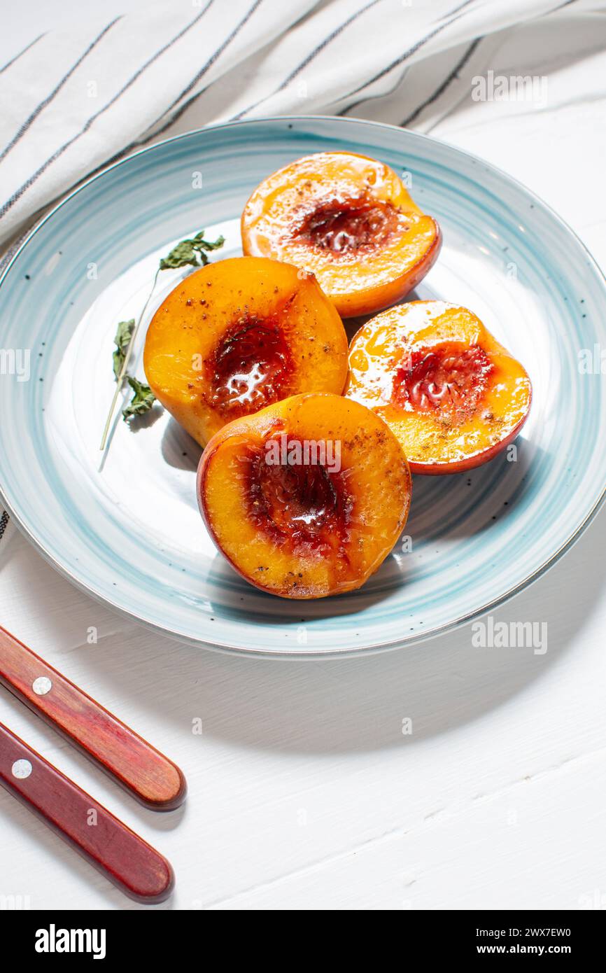 Baked peaches with honey and cinnamon in a ceramic plate. summer dessert. Stock Photo