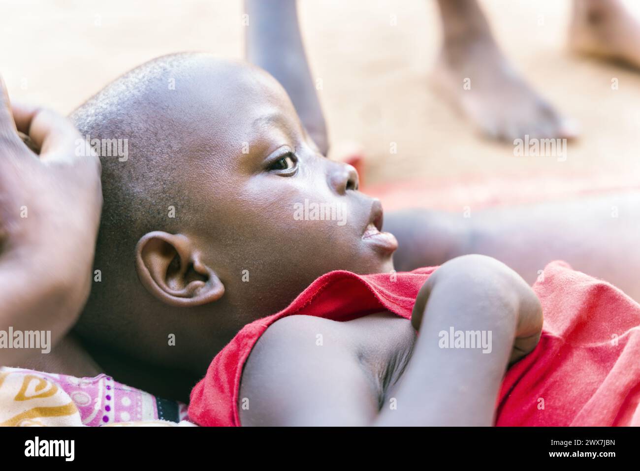 sick african child in an refugee camp, social worker comforting the boy, conflict zone Stock Photo