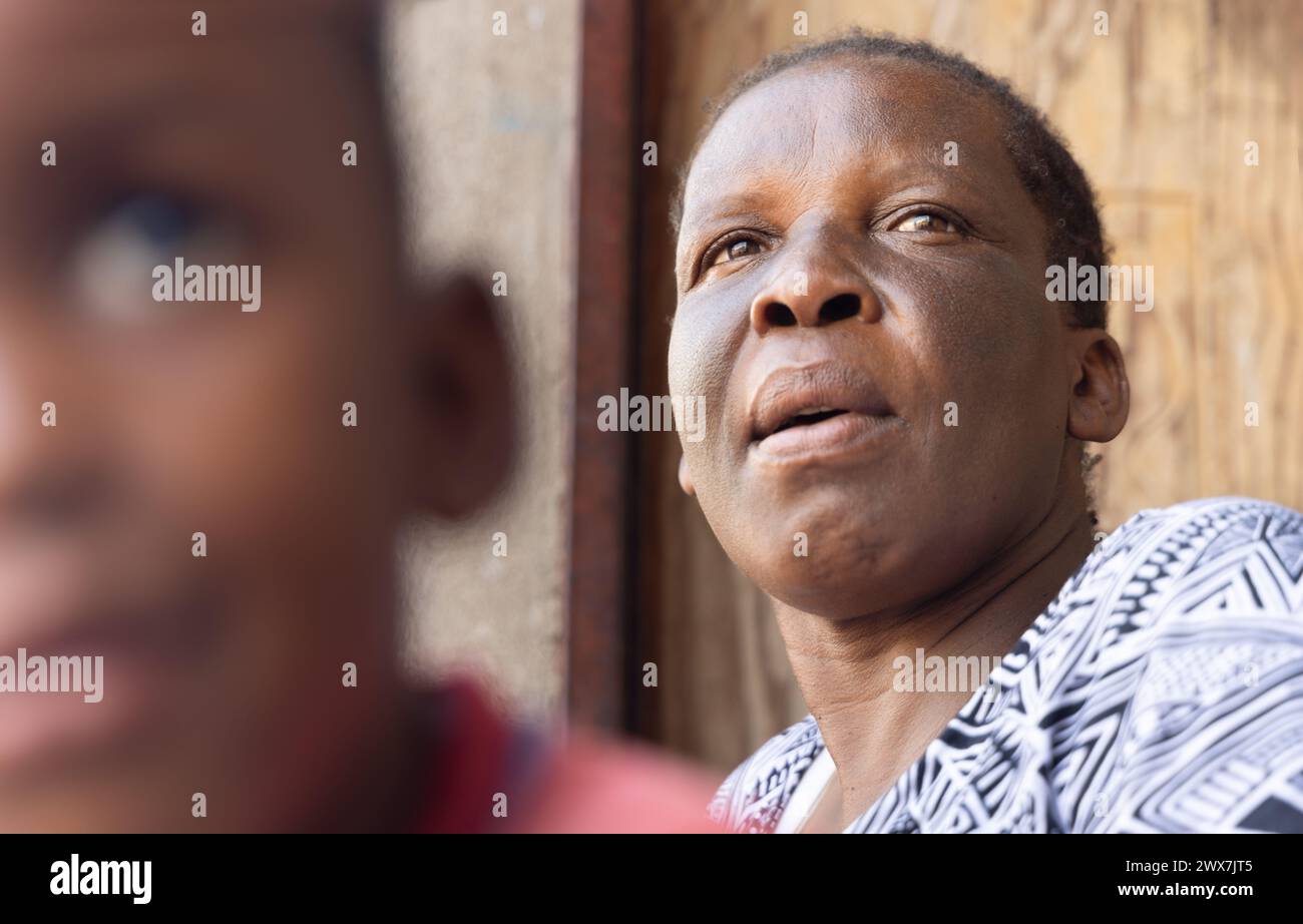 portrait of an african granny on the veranda, blurred child in the foreground, african village life Stock Photo