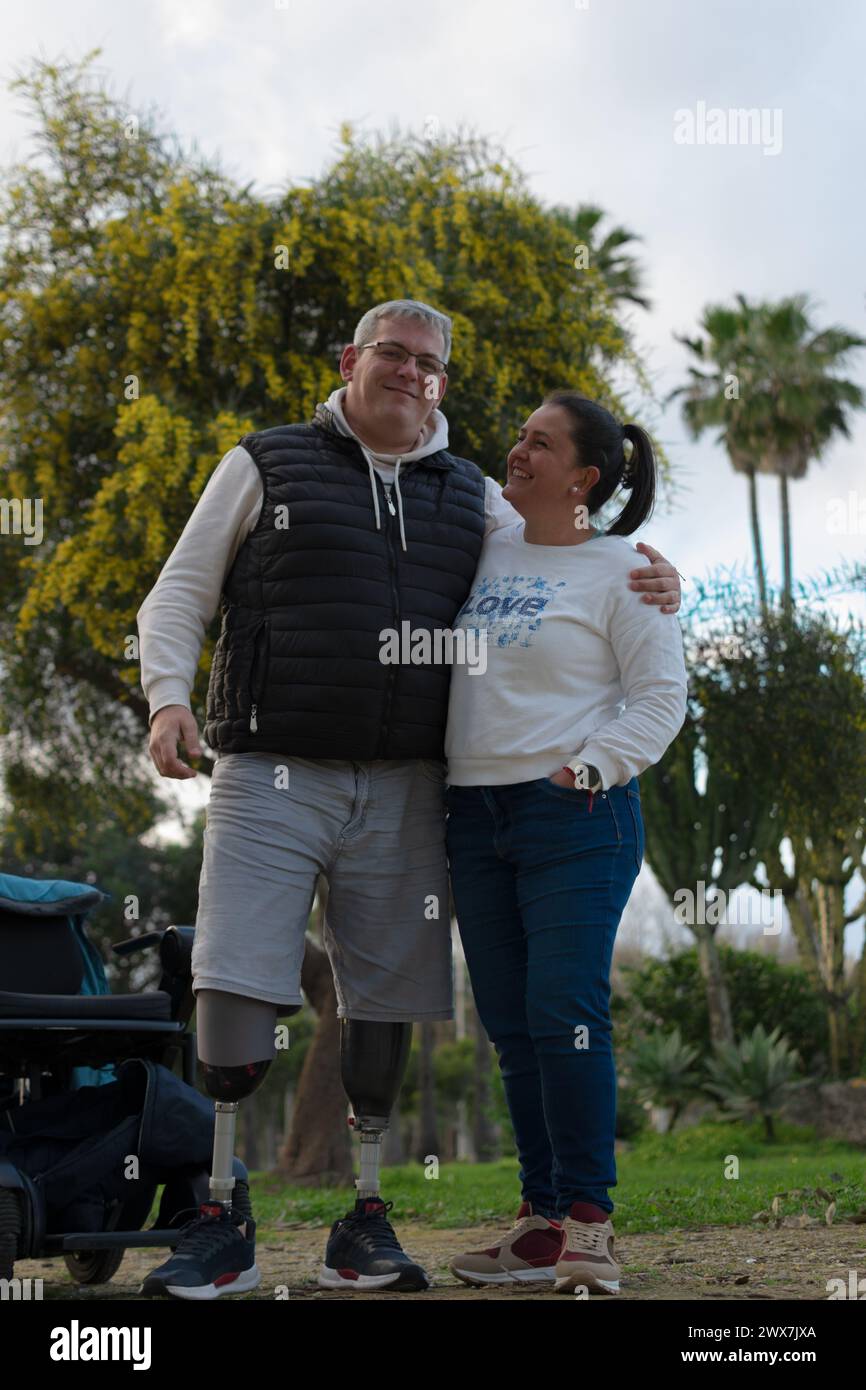 a couple poses happily in the park, following the recovery of her husband after the loss of both legs. Stock Photo