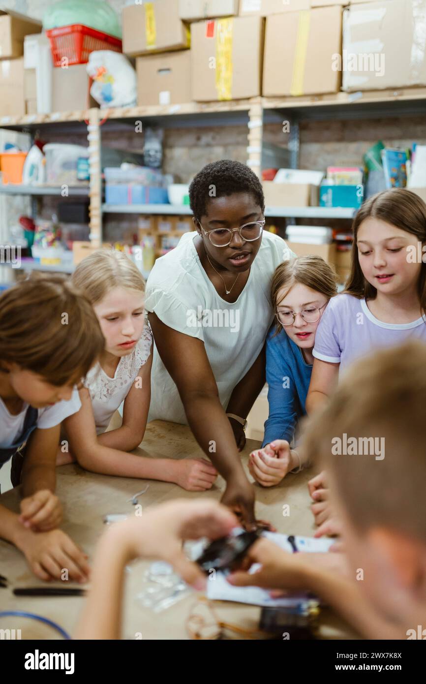Female teacher assisting group of students working on robotics project at workshop Stock Photo