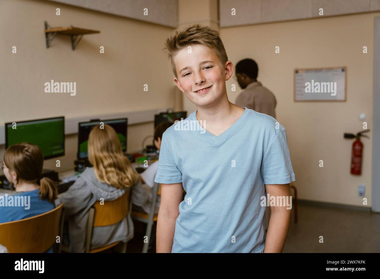 Portrait of smiling male student in computer classroom at school Stock Photo